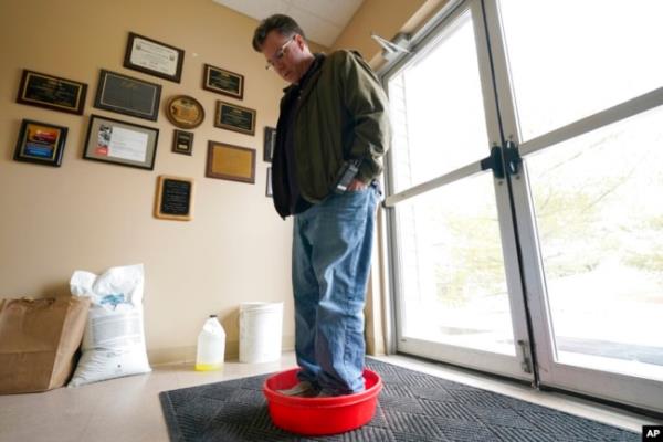 Ryan Bickel walks through a shoe disinfectant as he enters a building at the Blank Park Zoo, April 5, 2022, in Des Moines, Iowa. Zoos across North America are moving their birds indoors and away from people and wildlife as they try to protect them from avian influenza.