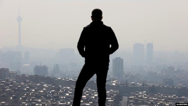 FILE - A man stands in front of a general view of Tehran city following the increase in air pollution in Tehran, Iran, Nov. 24, 2021. 