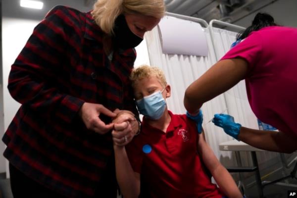 FILE - Heather Haworth, left, holds the hand of her 12-year-old son as he receives the Pfizer COVID-19 vaccine at the Providence, Edwards Lifesciences vaccination site in Santa Ana, Calif., May 13, 2021. FDA advisers are set to vote on whether to recommend the shot to kids younger than 5 years old.