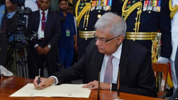 FILE - In this photo provided by Sri Lankan President's Office, Sri Lanka's newly elected president Ranil Wickremesinghe, signs after taking oath during his swearing-in ceremony in Colombo, Sri Lanka, July 21, 2022.