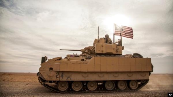 FILE - American soldiers drive a Bradley Fighting Vehicle during a joint exercise with Syrian Democratic Forces at the countryside of Deir Ezzor in northeastern Syria, Dec. 8, 2021.